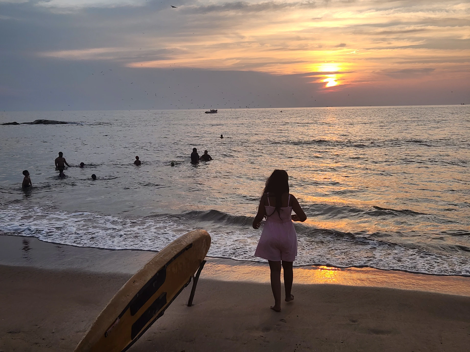 A serene beach scene at sunset with a model wearing a sleek, navy-blue swimsuit, embodying relaxed elegance by the ocean.