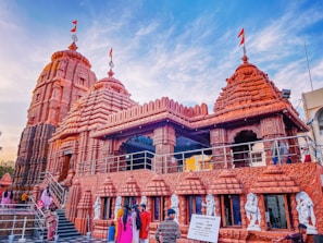 A group of pilgrims gathered outside the temple entrance, smiling and sharing stories under colorful flags.