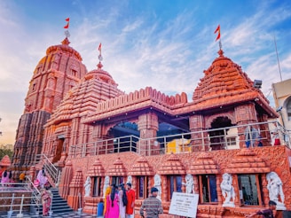 A group of pilgrims gathered outside the temple entrance, smiling and sharing stories under colorful flags.