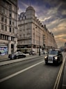 a black car driving down a street next to tall buildings