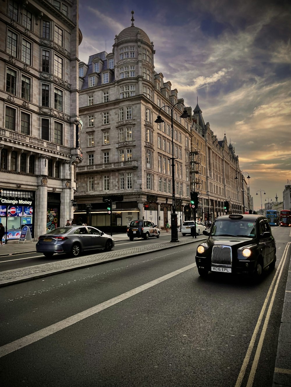 a black car driving down a street next to tall buildings