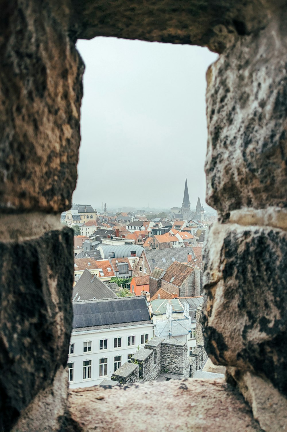 a view of a city through a hole in a stone wall