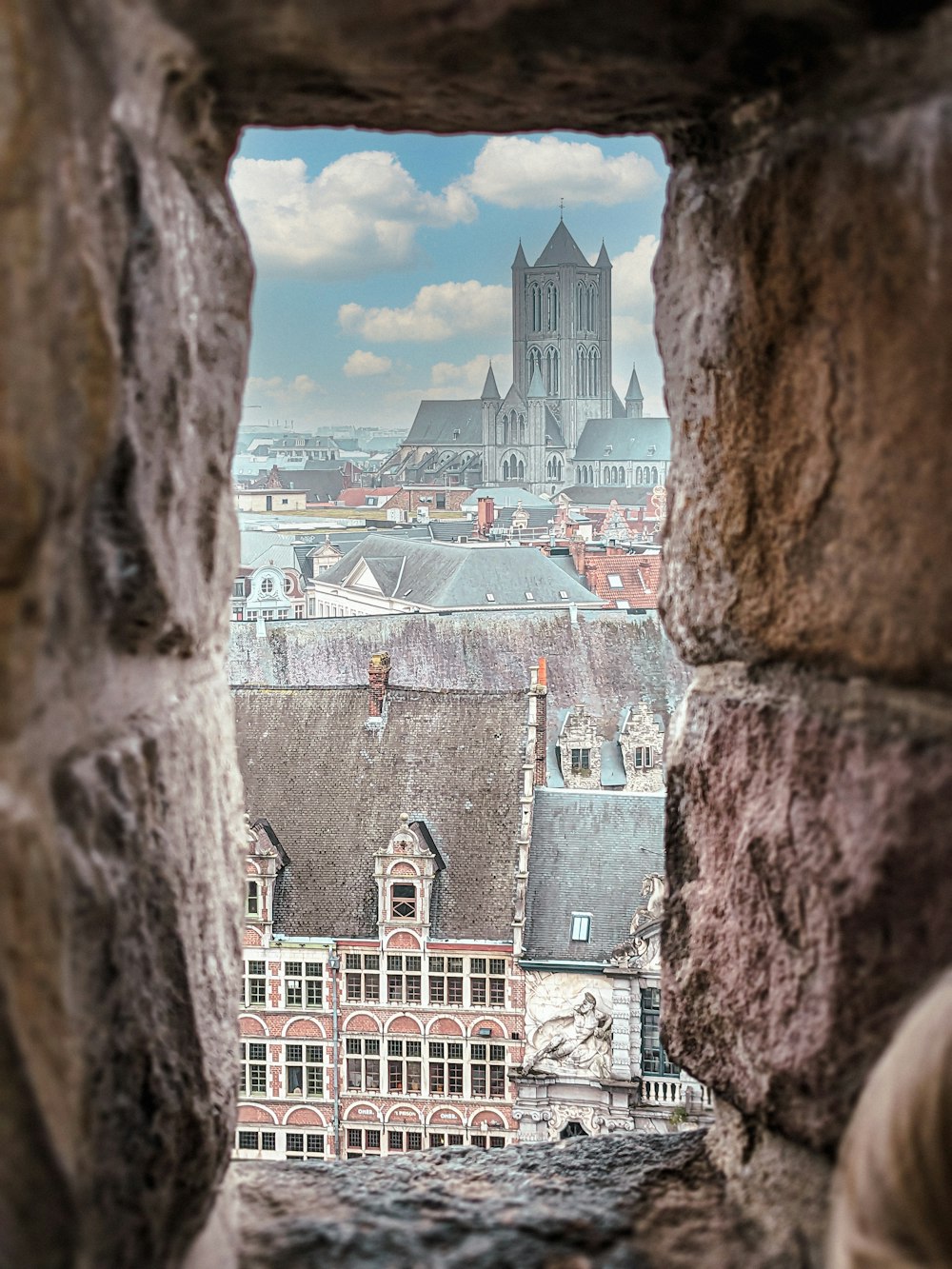 a view of a city through a hole in a stone wall