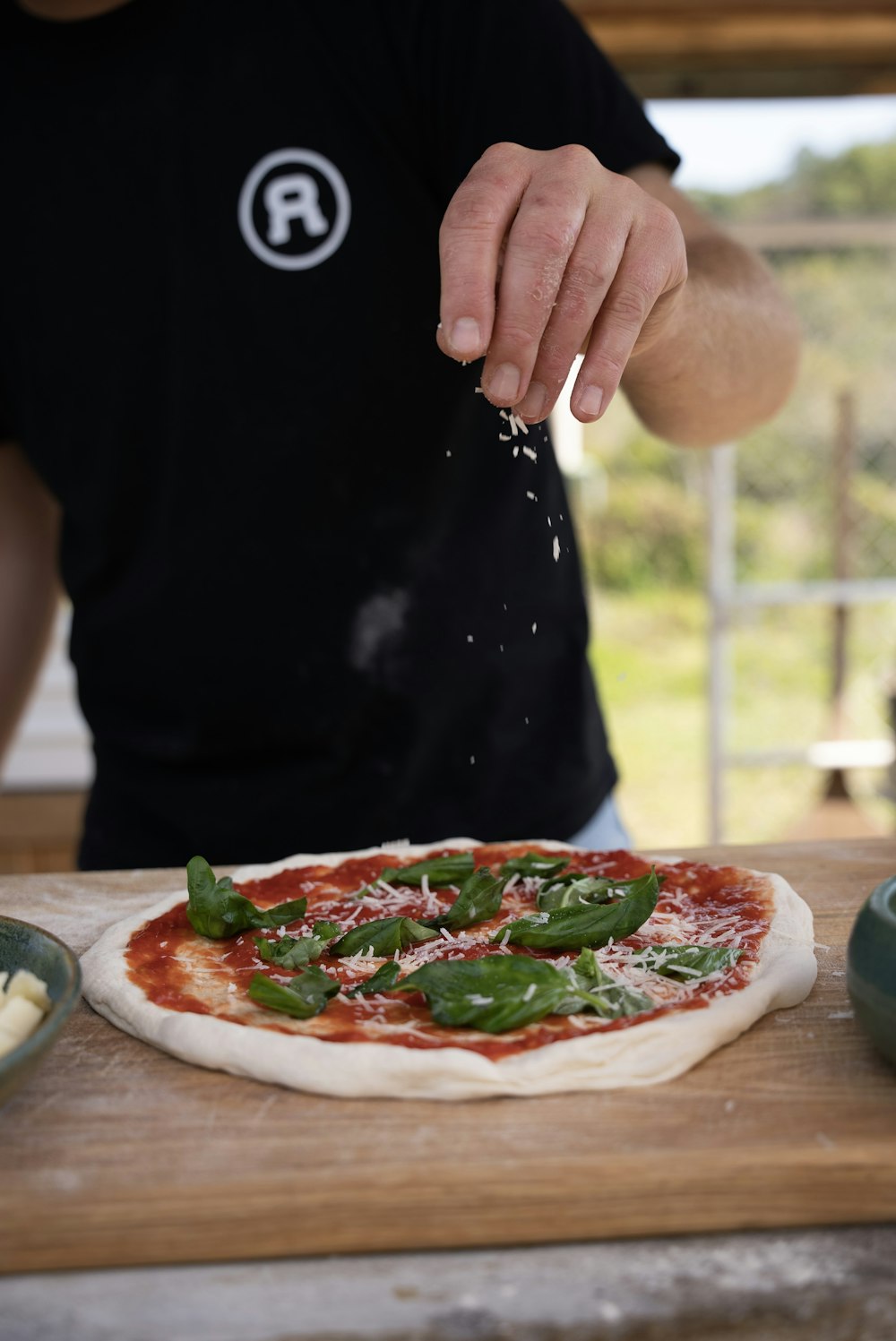 a man sprinkling cheese on top of a pizza