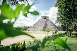 a large pyramid in the middle of a lush green field