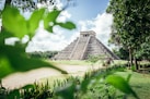 a large pyramid in the middle of a lush green field