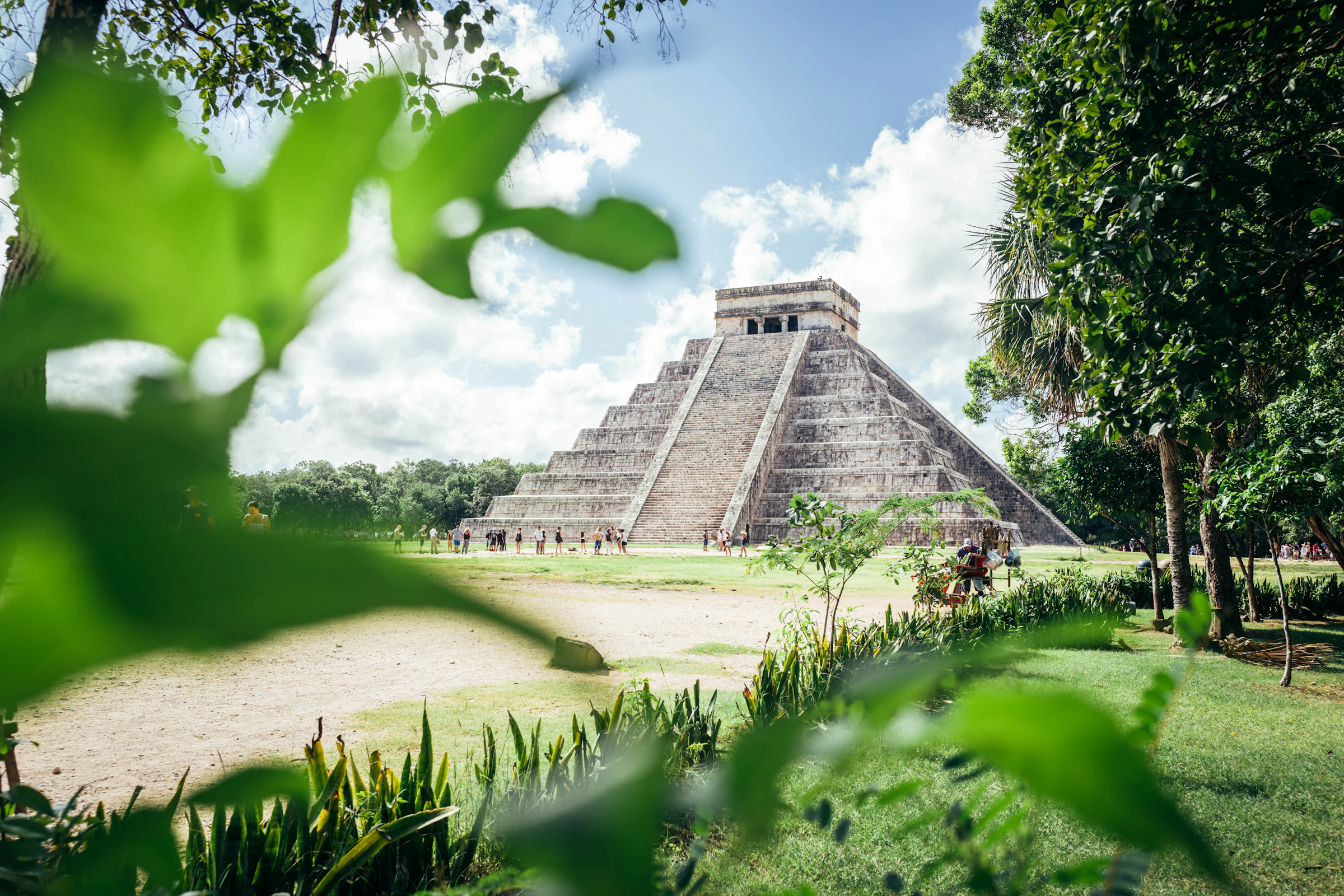 Wide view of the Chichen Itza pyramid surrounded by lush green jungle