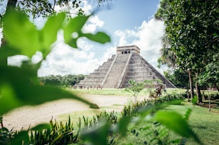 a large pyramid in the middle of a lush green field