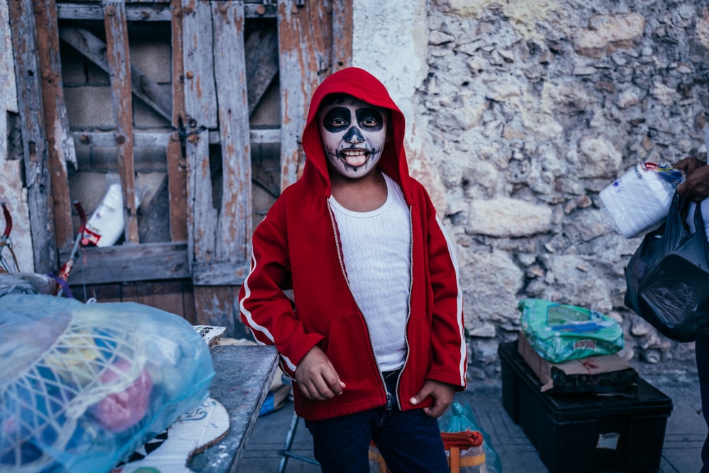 a young boy wearing a skeleton mask and a red jacket
