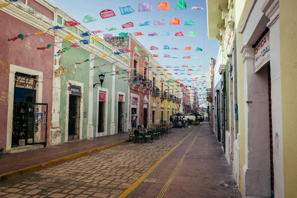A street lined with colorful buildings and flags — Valladolid, Mexico