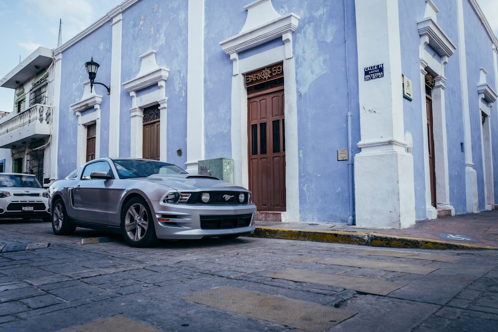 a silver car parked in front of a blue building