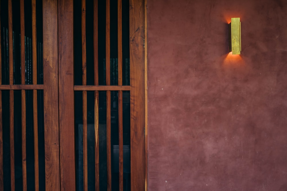 a red wall with a wooden door and a light on it