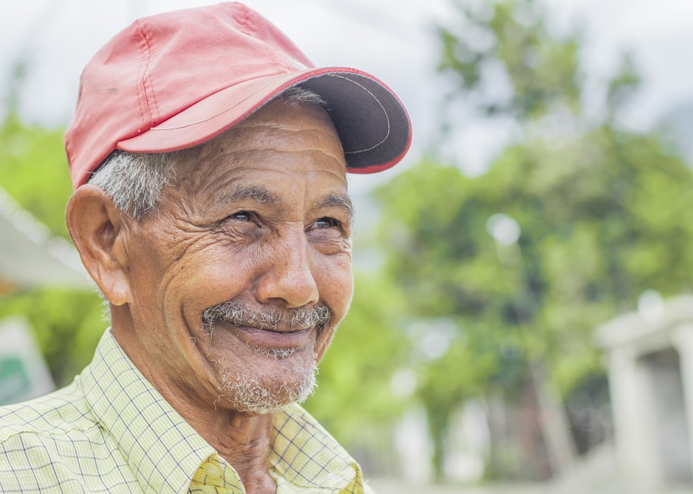 an older man wearing a red hat and a green shirt