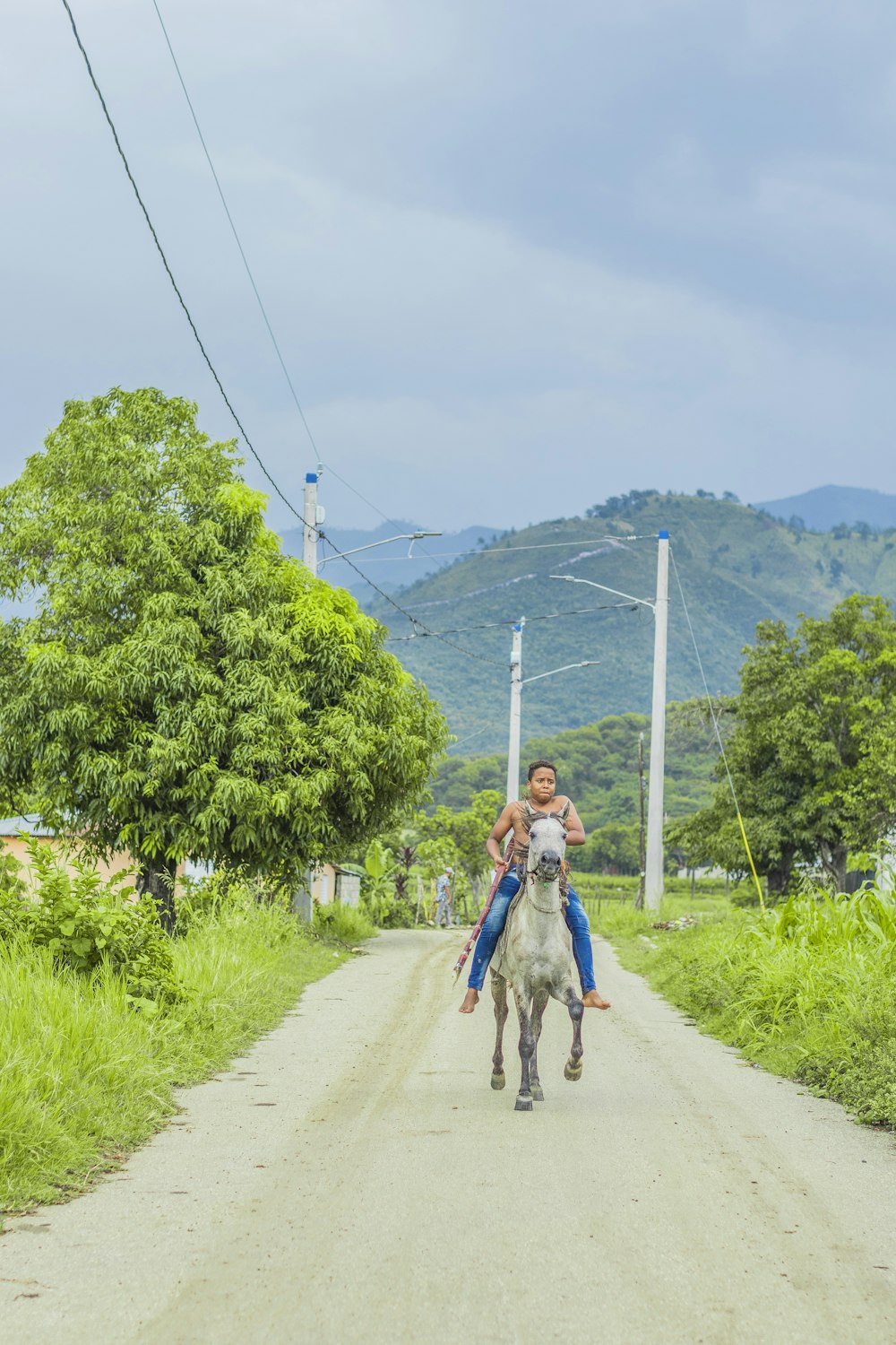 a man riding on the back of a white horse down a dirt road