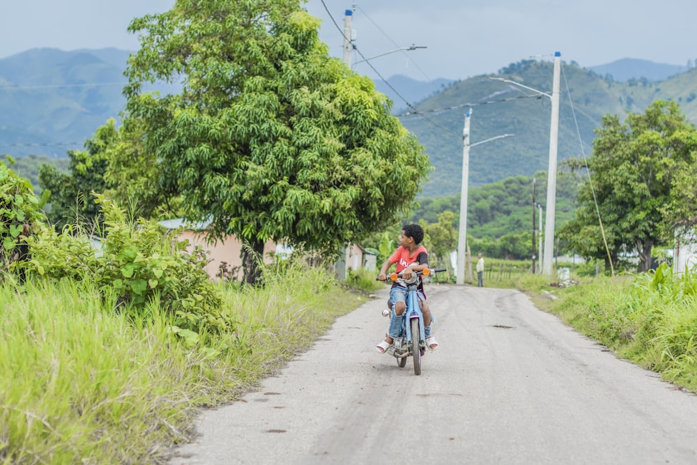 a young boy riding a bike down a dirt road