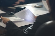 a woman sitting at a table reading a paper