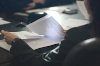 Mujer sentada a la mesa leyendo un documento.