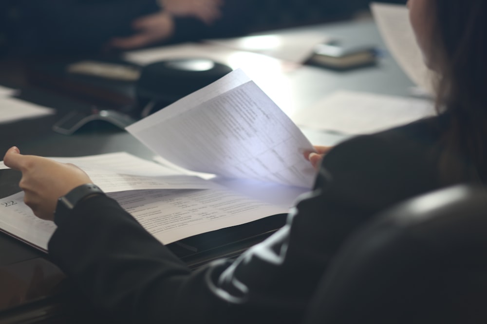 a woman sitting at a table reading a paper