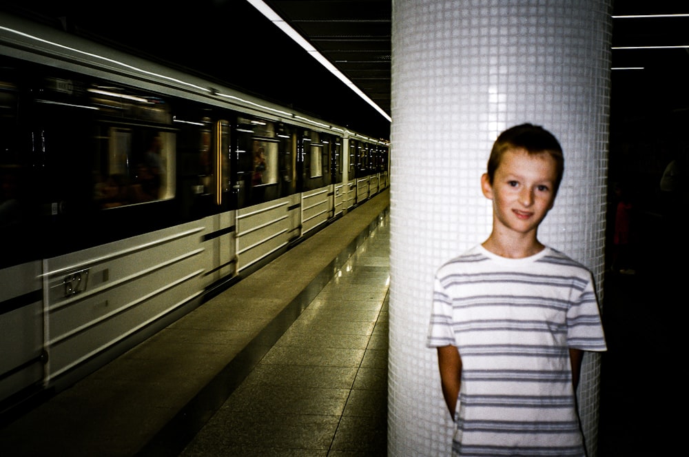 a young boy standing next to a subway train