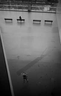 Wide-angle view of the gallery’s main hall featuring minimalist black benches and soft grey walls.
