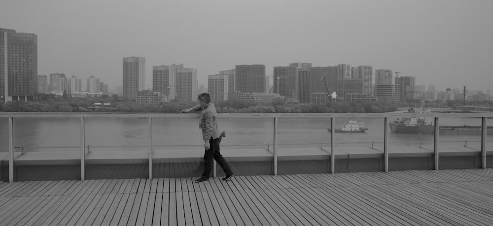 a man is standing on a boardwalk looking at the water
