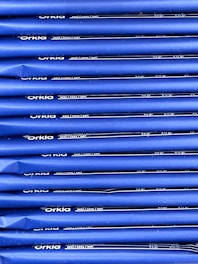 An array of blue packages stacked neatly in rows with 'Orkla' branding and nutritional information printed in white. The packaging appears uniform and organized.