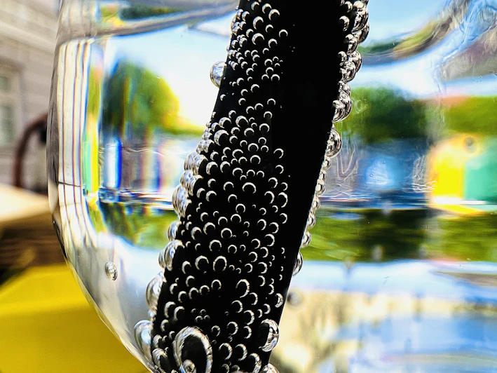 Close-up of a clear glass filled with sparkling alkaline water and condensation droplets.
