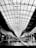 A shopping mall atrium with an intricate, geometrically designed ceiling made of glass and metal. There are storefronts lining both sides, featuring various signs and displays. The central walkway has a couple of people and a shopping cart visible.