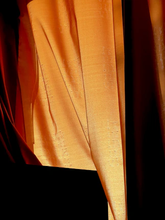 Burnt orange fabric draped elegantly, capturing Tuesday's warm, serious tone.