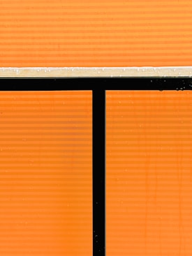 Panels with a bright orange background divided by black and white lines. The surface appears to be a window or partition with a modern, minimalist design.