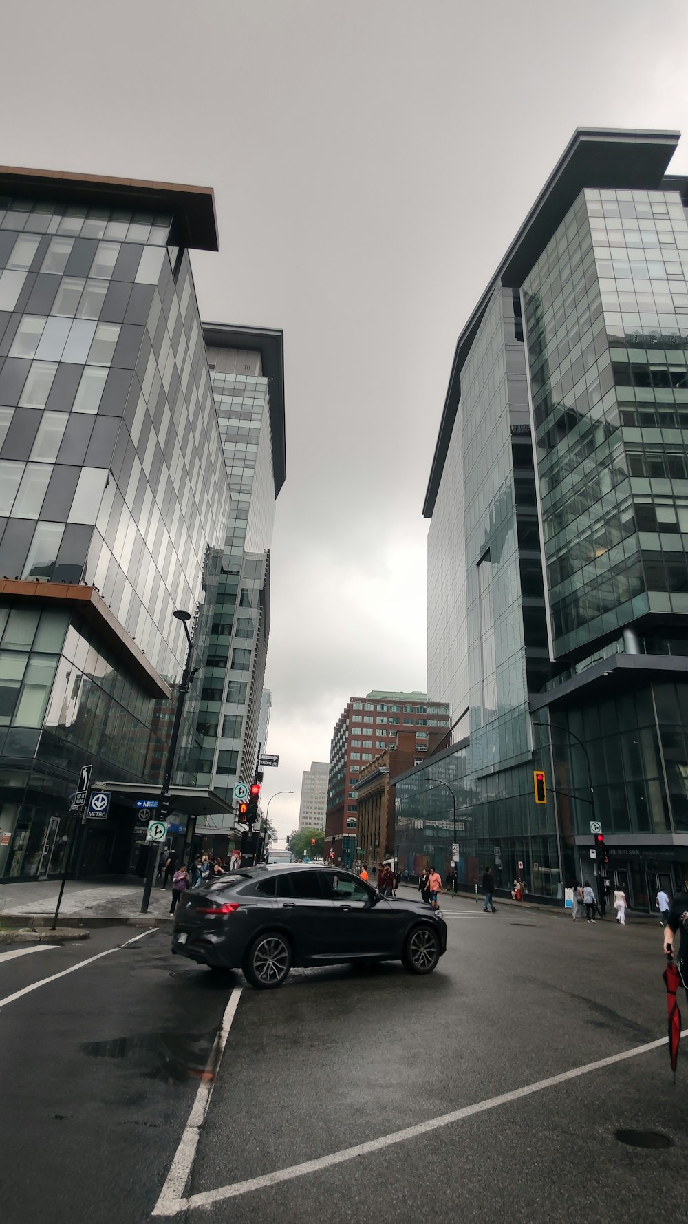 a black car driving down a street next to tall buildings