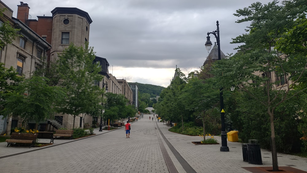 a couple of people walking down a street next to tall buildings