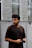 Image of a thoughtful man looking at a smartphone, standing against a minimalistic background.