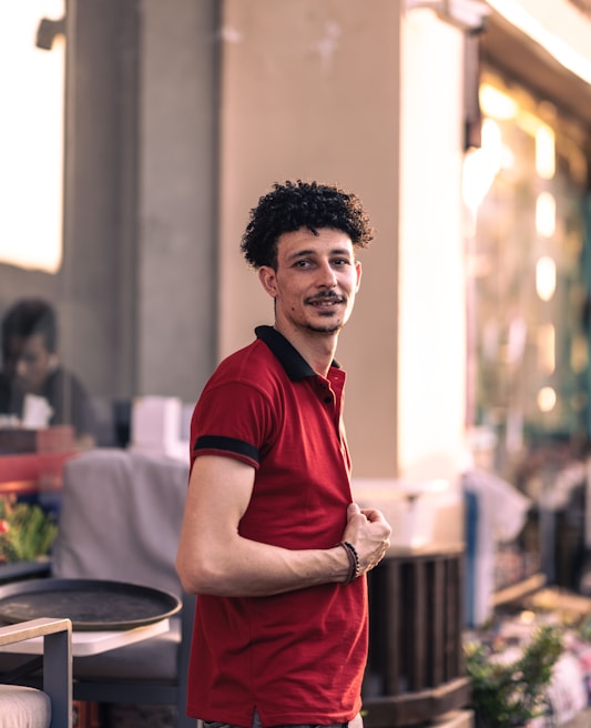 Model wearing a vibrant red prime polo t-shirt paired with casual jeans outdoors
