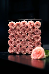 A beautifully arranged round acrylic flower box with vibrant fresh roses.