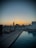 Elegant rooftop pool area with lounge chairs and cityscape at sunset.