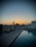 A smiling resident relaxing by the poolside with the city skyline in the background at sunset.