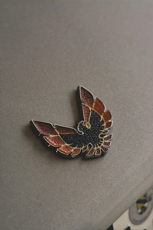 Close-up of a worn badge stained with red, resting on a cracked concrete surface.