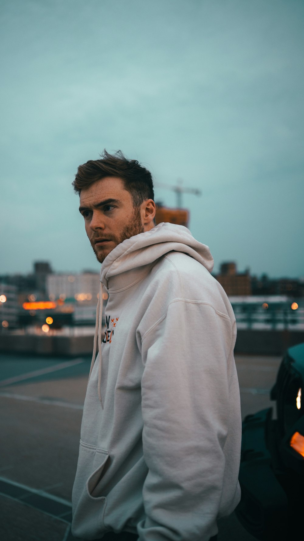 a man in a white hoodie standing on a street