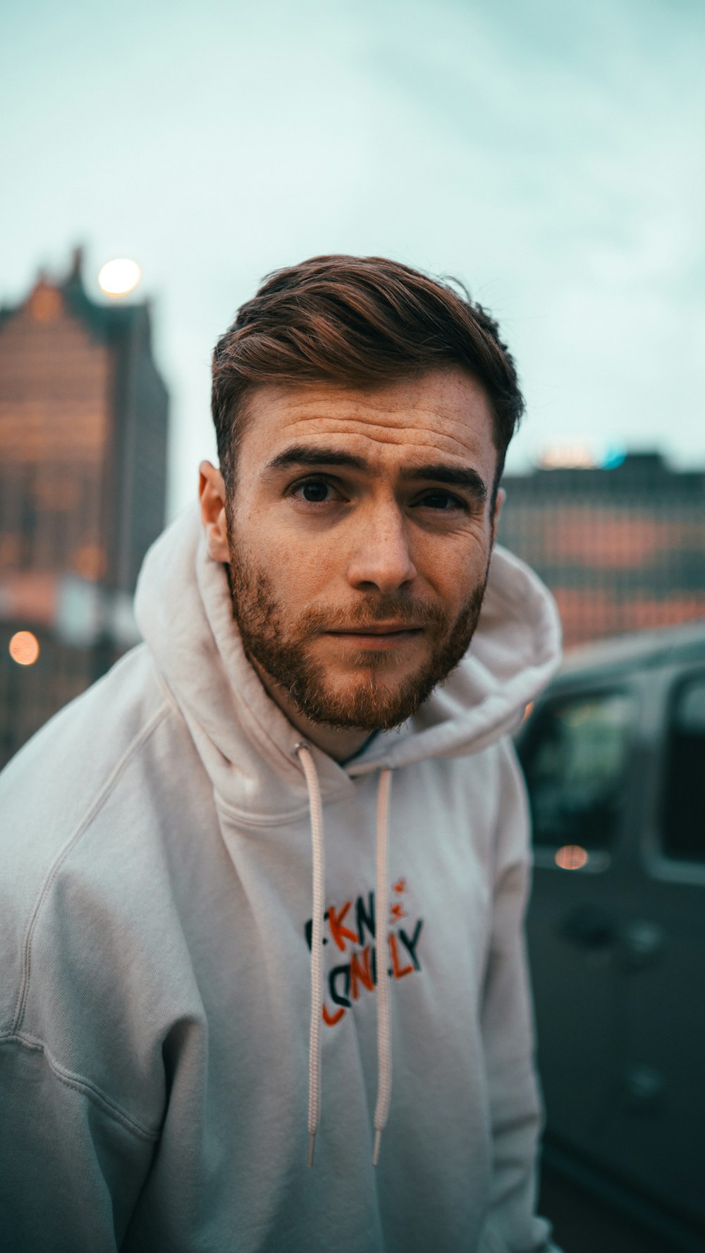 a man with a beard and a white hoodie