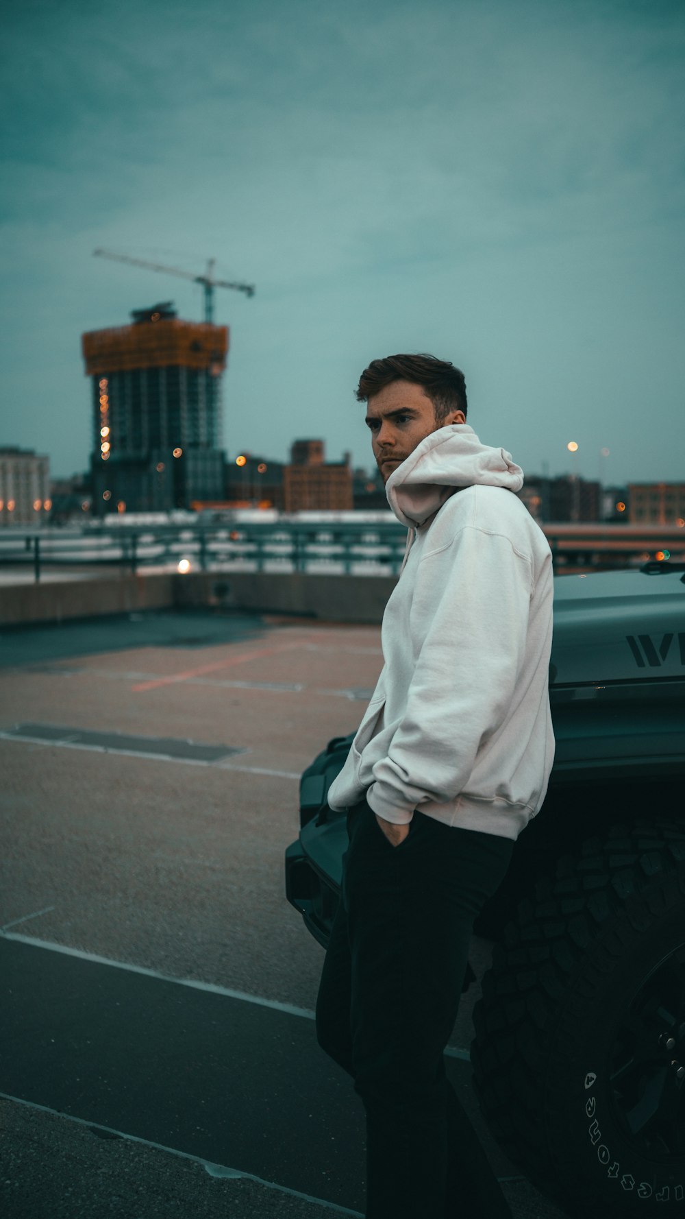 a man standing next to a car in a parking lot