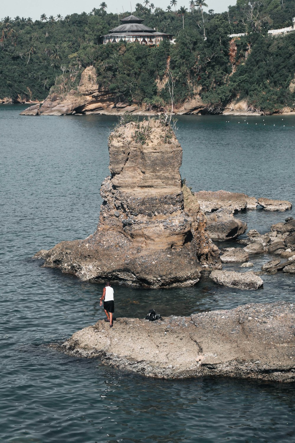 a person standing on a rock in the middle of a body of water