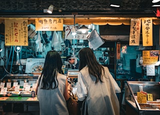 a couple of women standing next to each other in front of a store