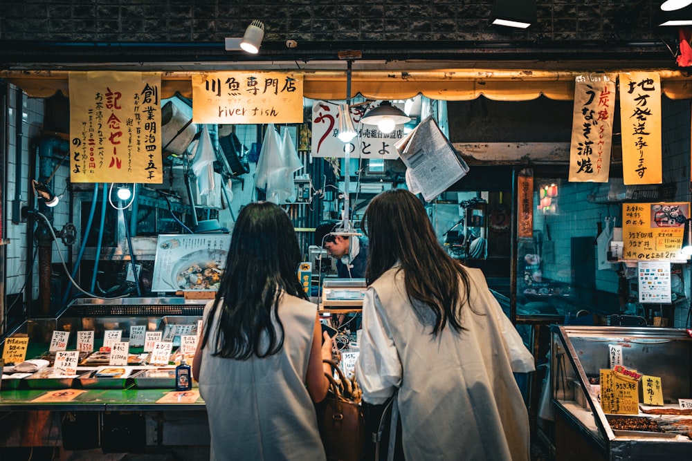 a couple of women standing next to each other in front of a store