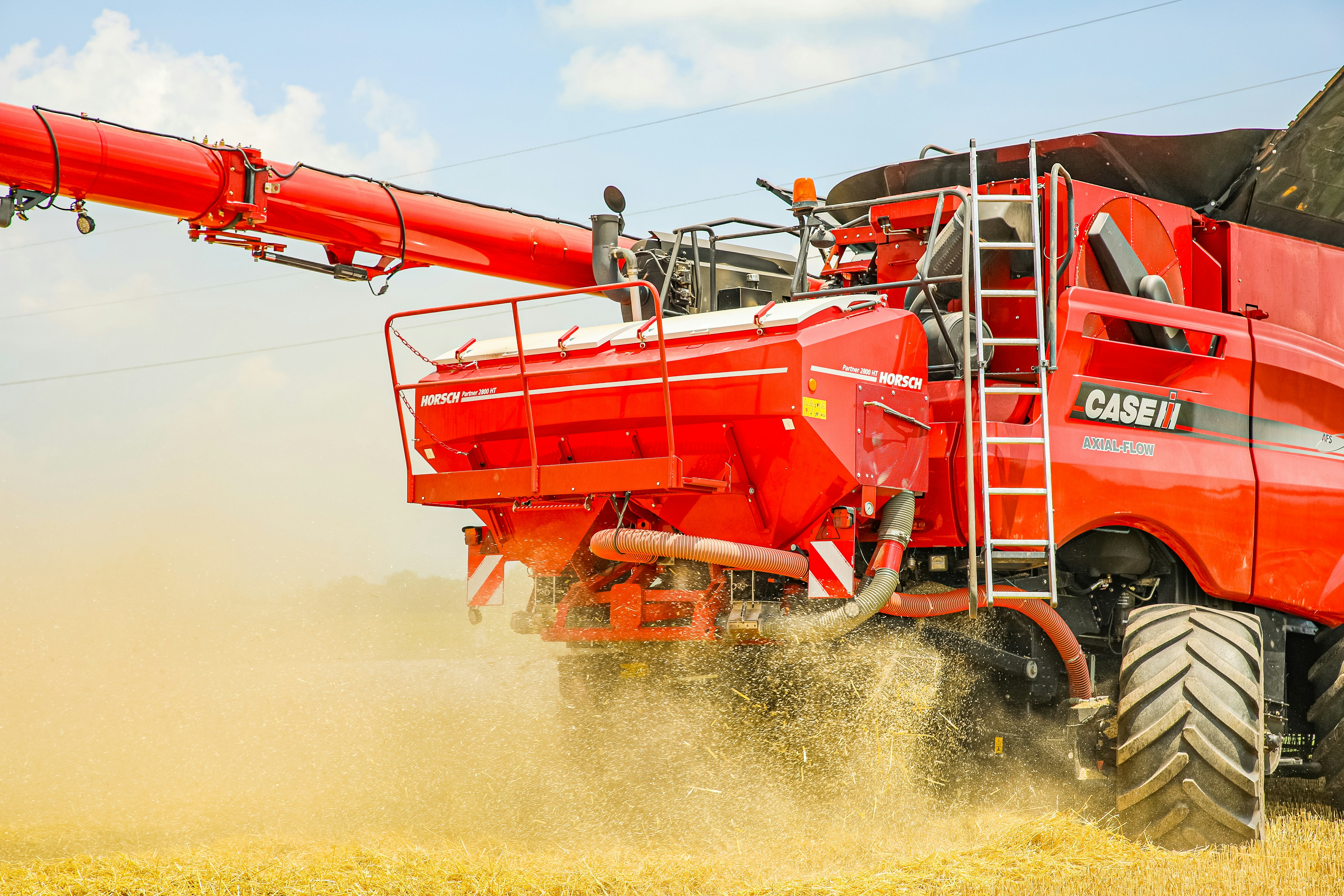 a large red truck driving through a wheat field
