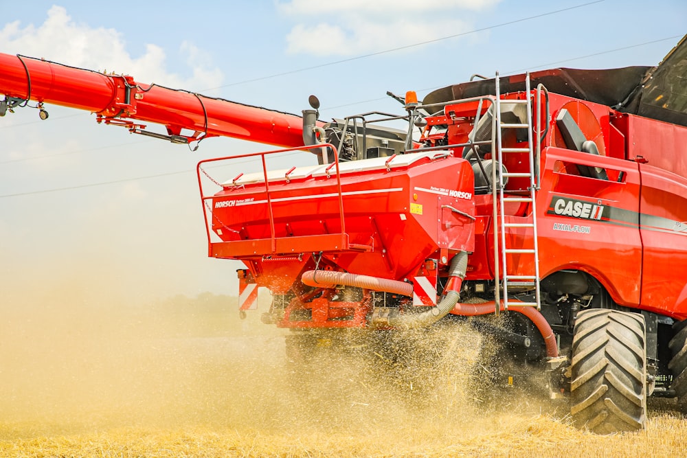 a large red truck driving through a wheat field