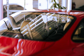 Dynamic shot of a sports car’s side window showcasing expertly tinted glass with a subtle red background glow.