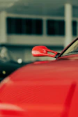 Close-up of a sleek car rearview mirror with a dark gray and red accent background.