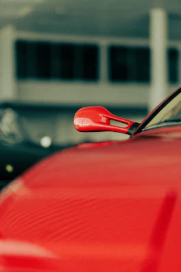 Close-up of a sleek car rearview mirror with a dark gray and red accent background.