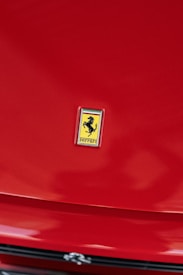 A bright red car hood prominently features the emblem of a prancing horse against a yellow background, signifying a luxury brand.
